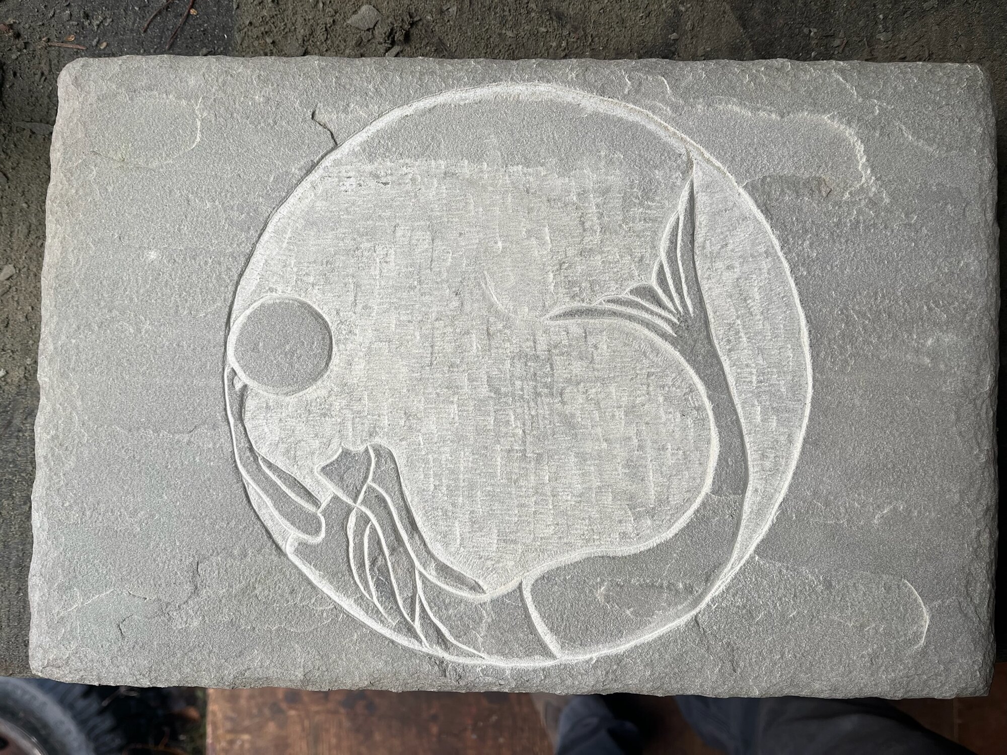 Carved mermaid and fish medallion in stone