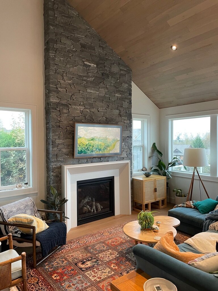 Dark slate fireplace surround under a vaulted wood ceiling