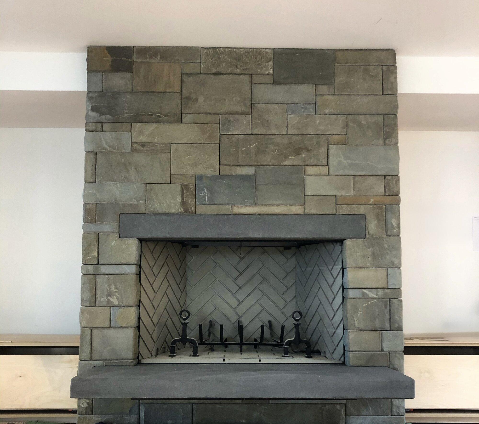 Flagstone fireplace with herringbone firebox and iron andirons