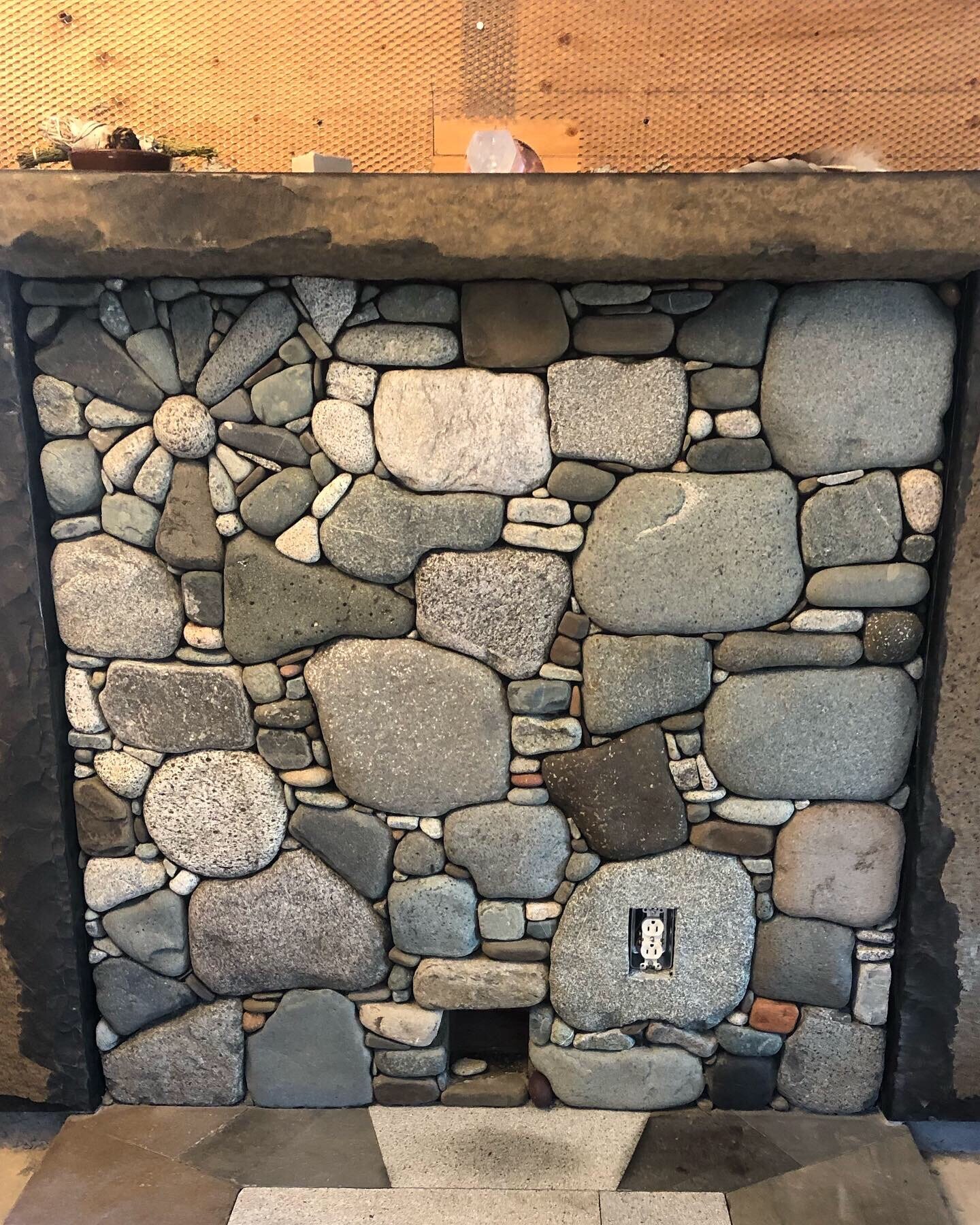 Close-up of a pebble mosaic fireplace with a flower medallion