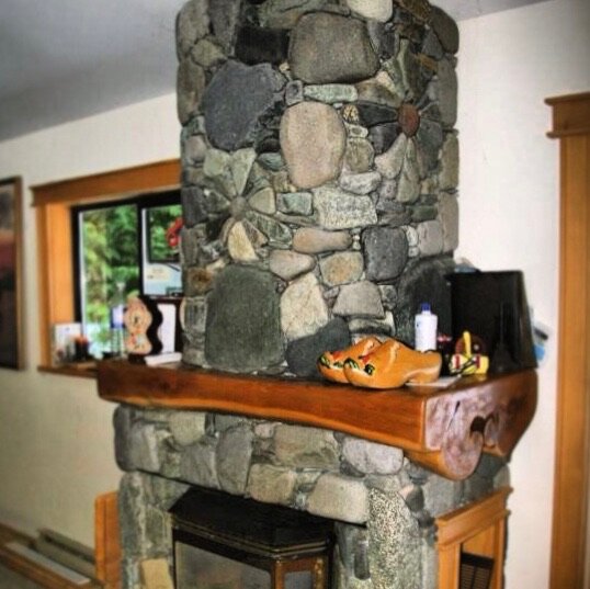 Round river rock chimney with a live-edge wood mantle