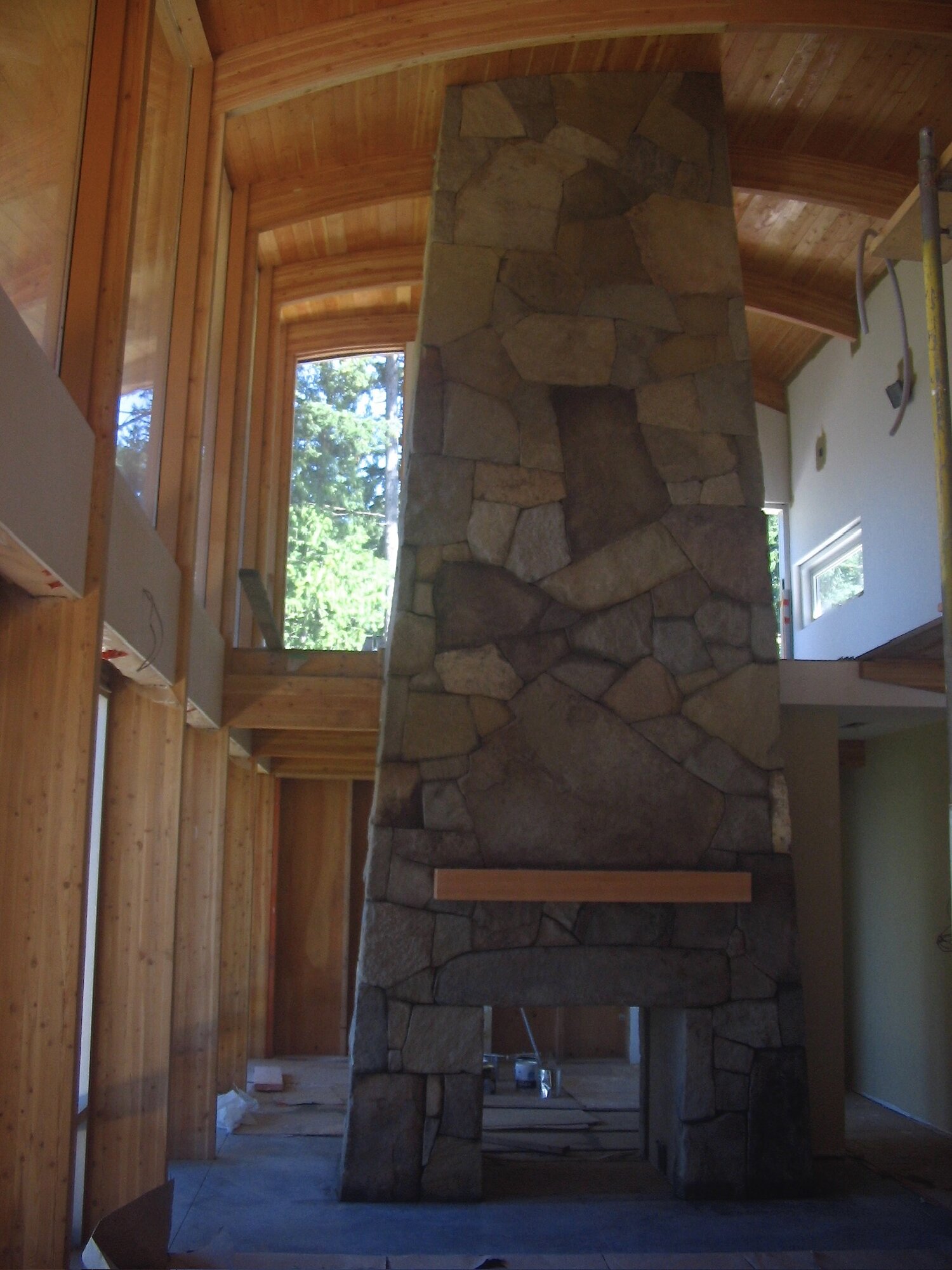 Tall flagstone fireplace beneath a curved wood ceiling