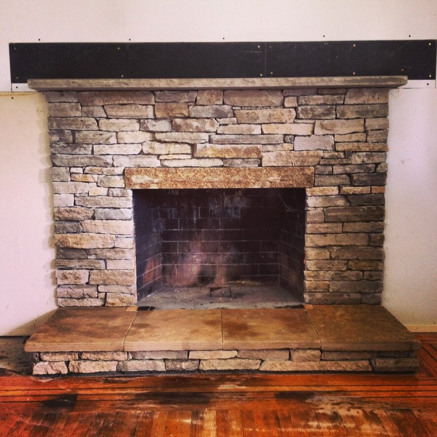 Tan dry-stack stone fireplace with a granite lintel