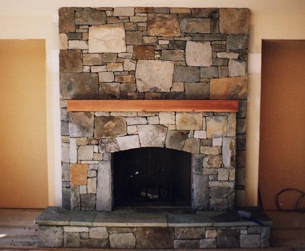 Traditional river rock fireplace with an arched firebox opening