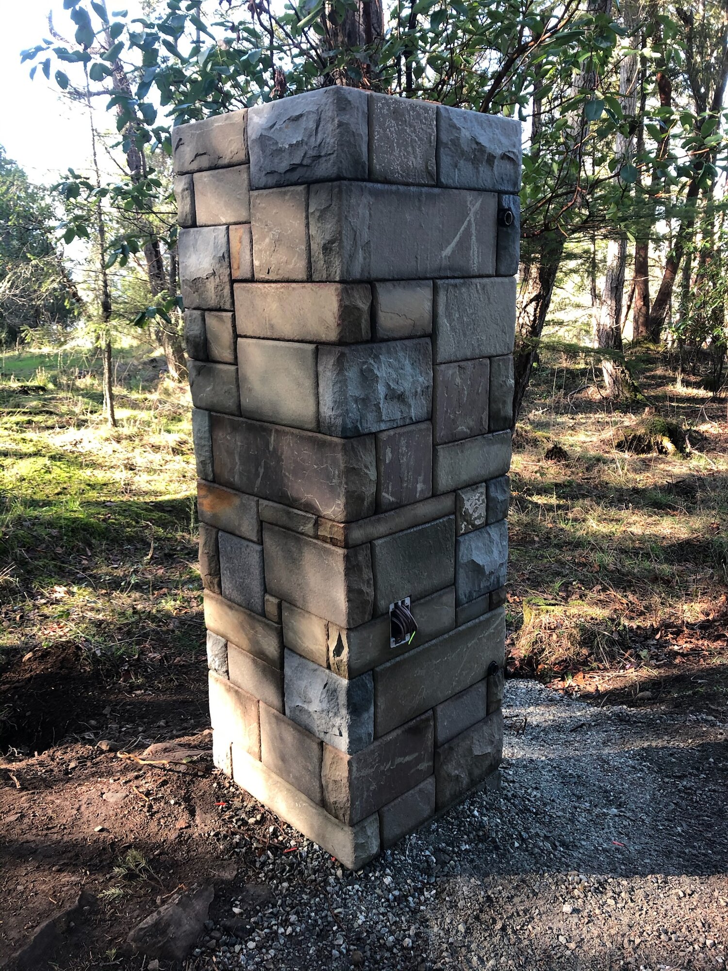 Tall stone gate pillar at a forest entrance
