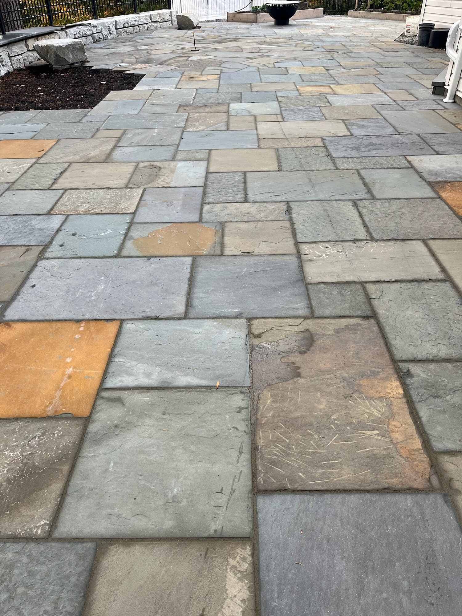 Large flagstone patio in an irregular pattern with a fire bowl in background