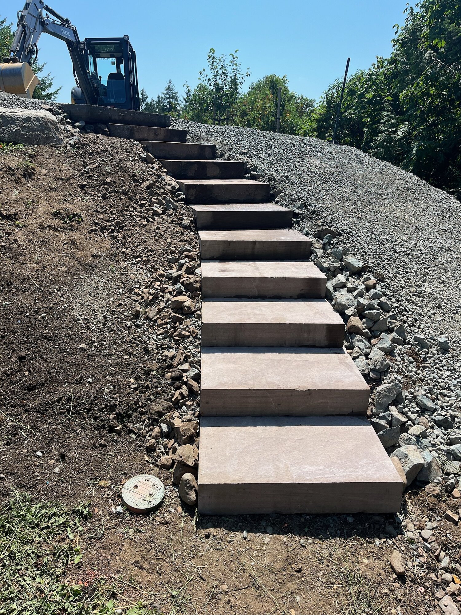 Long run of rose granite steps up a hillside, new construction with excavator