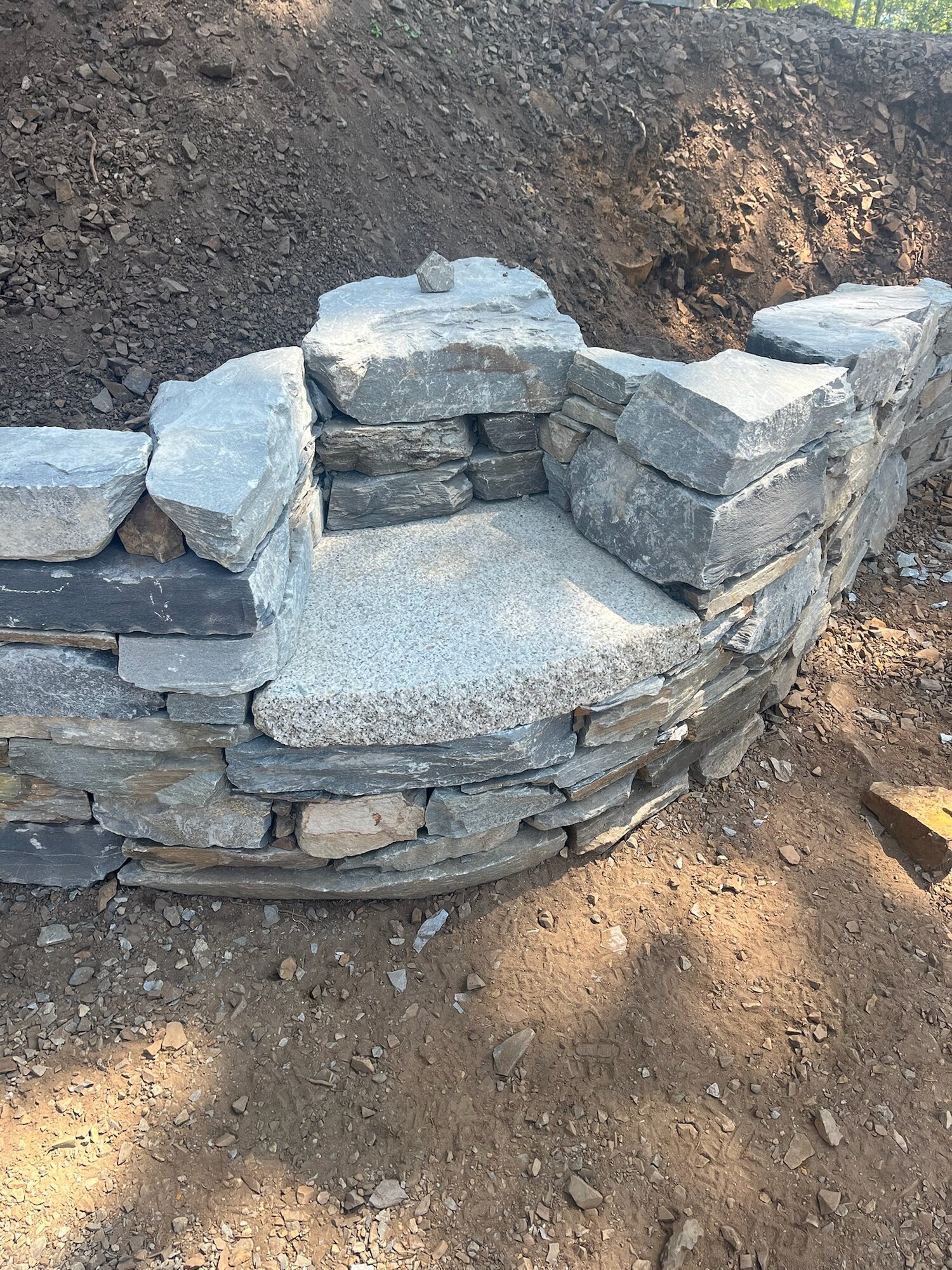 Curved dry-stack wall with a granite seat inset, new construction