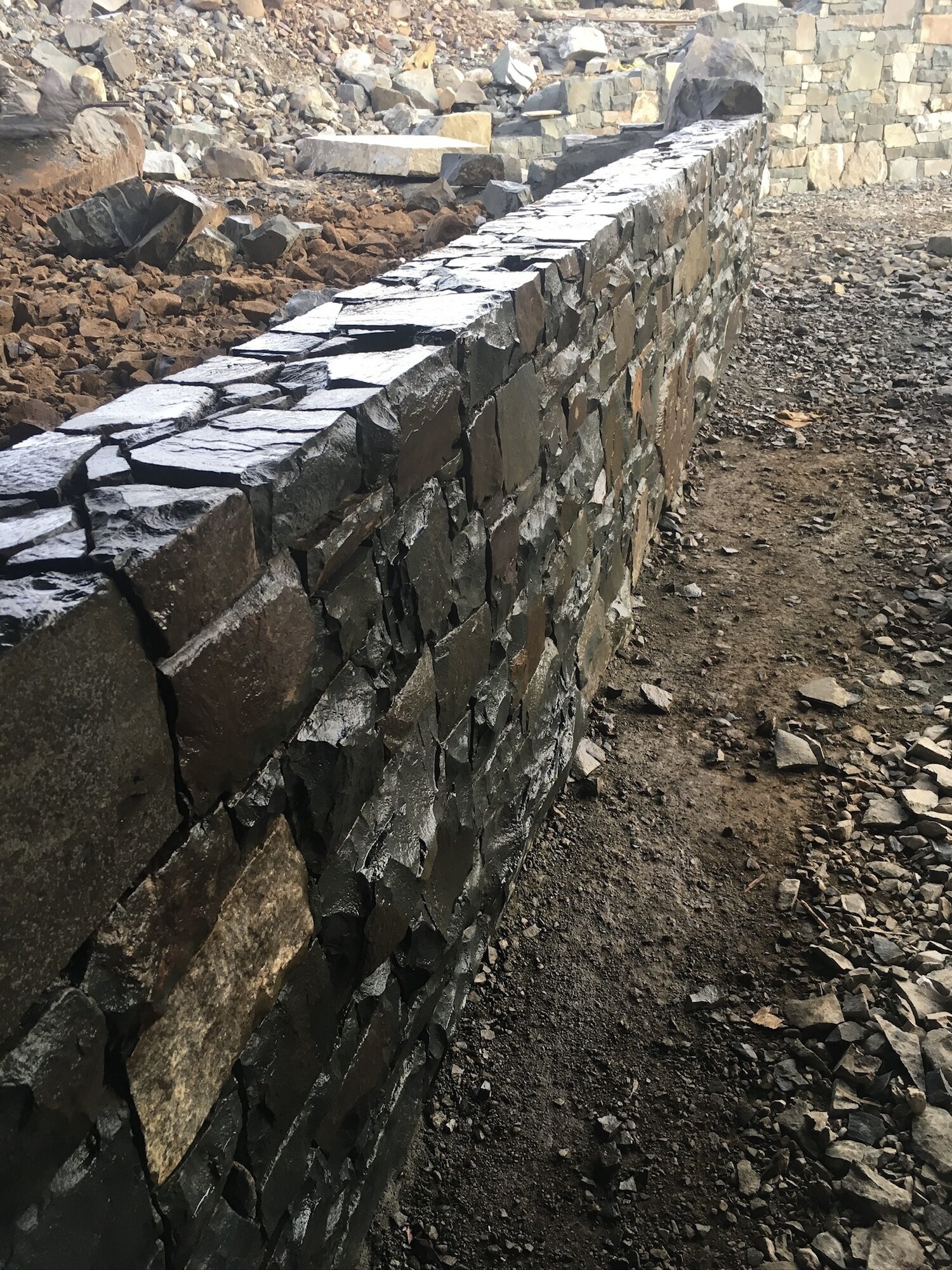 Dry-stack stone retaining wall along a gravel pathway