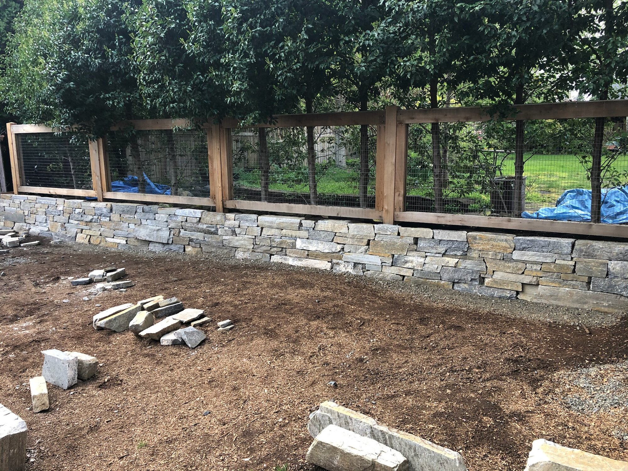 Dry-stack stone wall below a wire fence