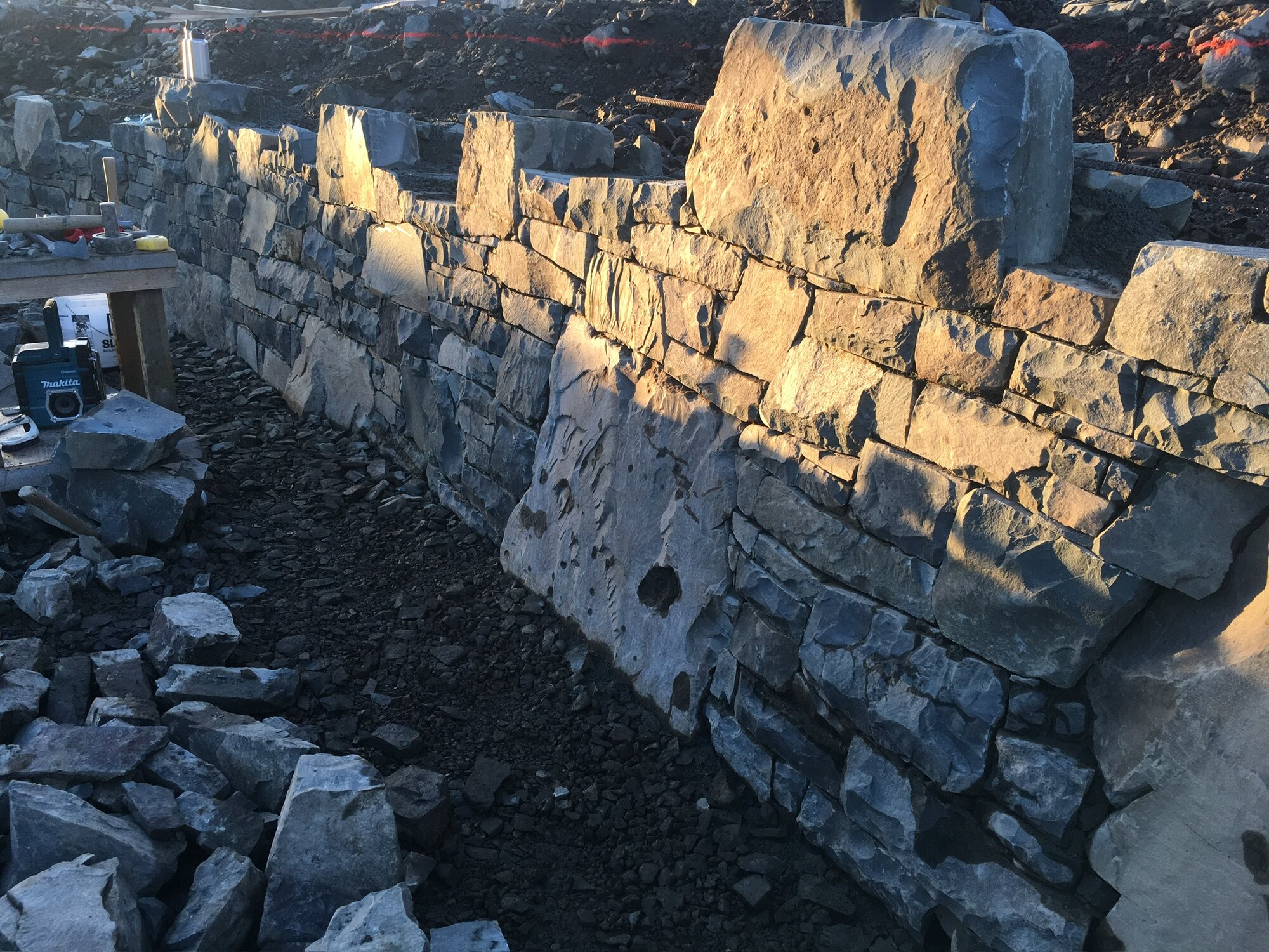 Fieldstone wall under construction in golden-hour light