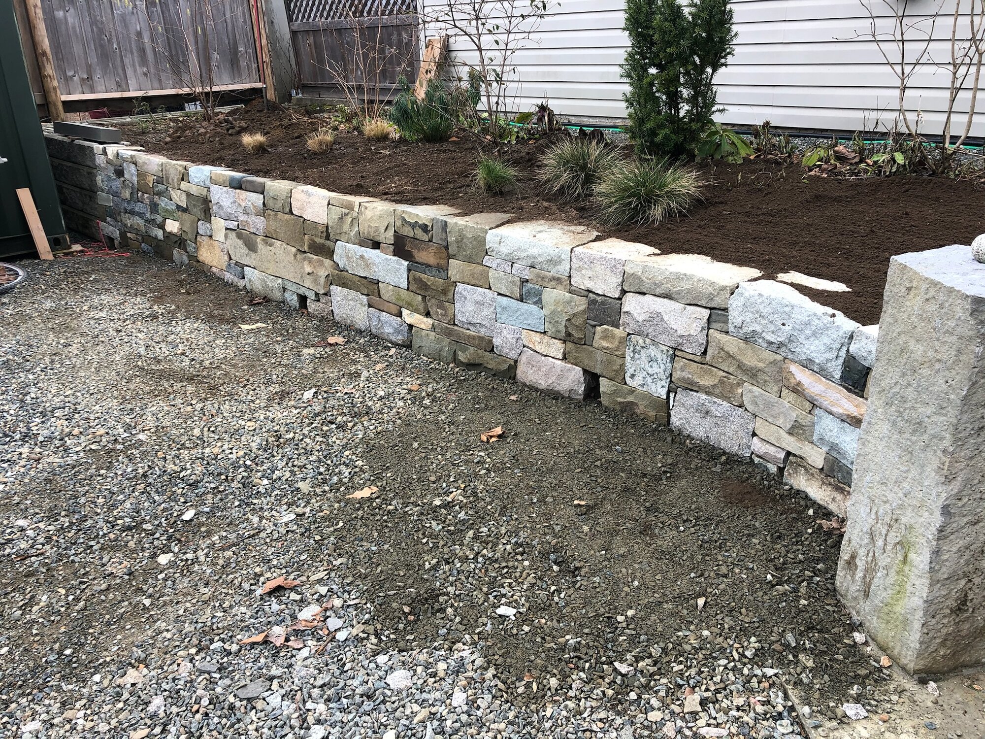Mixed stone retaining wall bordering a garden bed